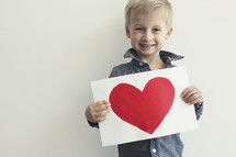 toddler boy holding a painting of a heart 