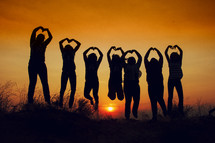 silhouette of girls making heart shapes 