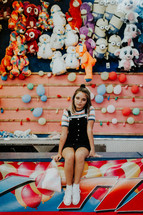 a teen girl at a carnival game booth at a fair 