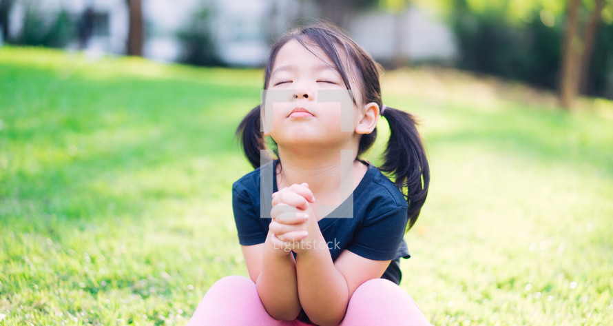 a toddler girl with praying hands 