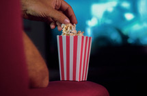 a man eating popcorn watching movies 
