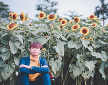 a young man sitting in a field of sunflowers 