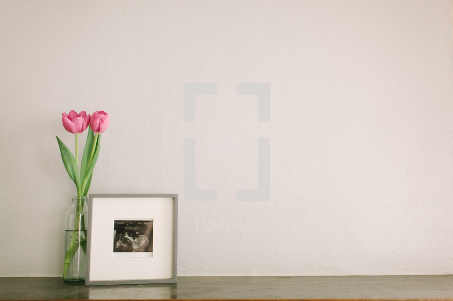 pink tulip in a vase and a framed picture 
