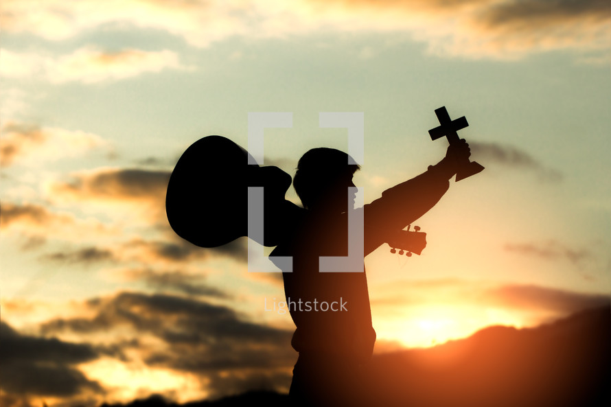 young christian worshipping God by holding cross and with light sun