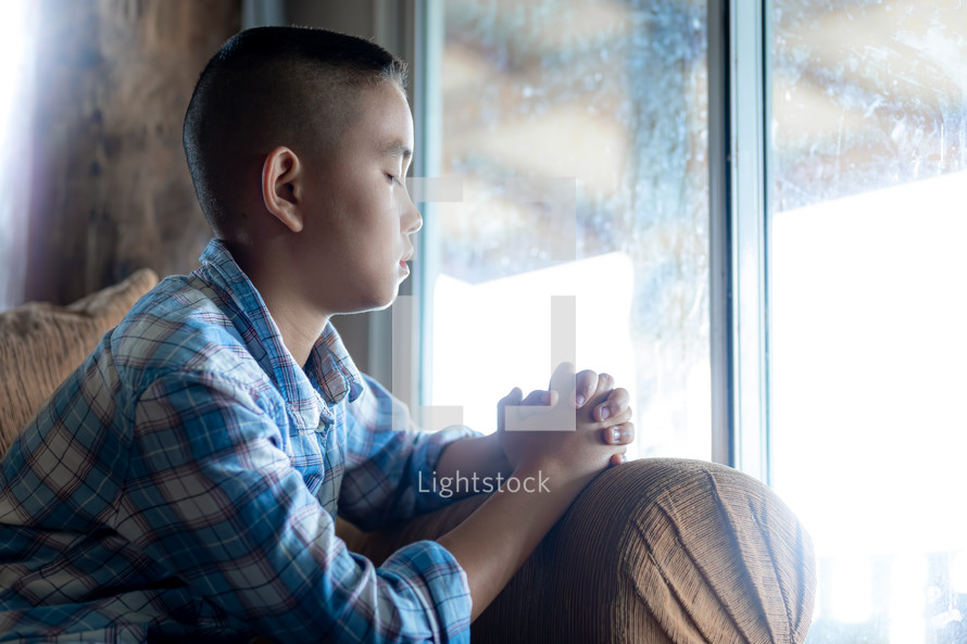 boy praying in a window 