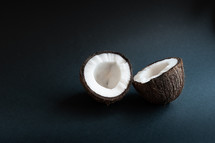 two halves of coconut on a black background with copy space