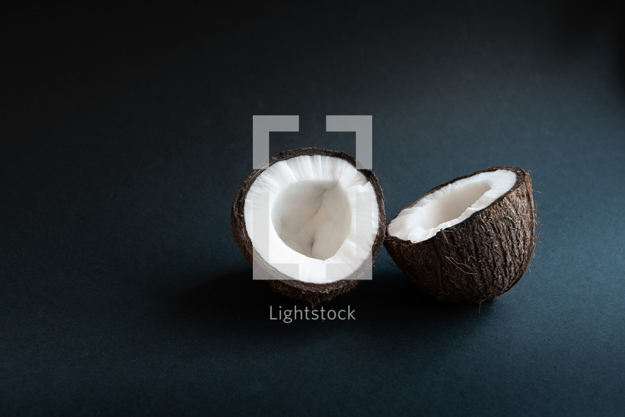 two halves of coconut on a black background with copy space