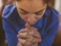 A young woman with her hands folded in prayer