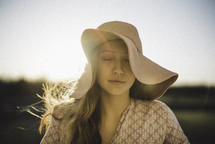 a young woman with closed eyes in a sun hat 