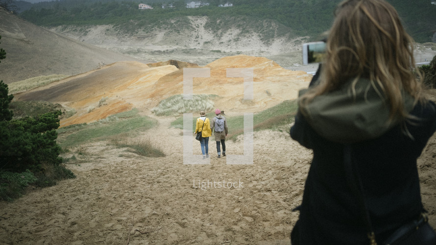 woman filming her friends walking down a hill 