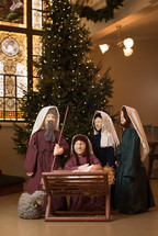 Christmas tree and figurines of Mary, Joseph, and Baby Jesus in a church 