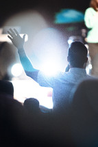 man with hands raised at a worship service 