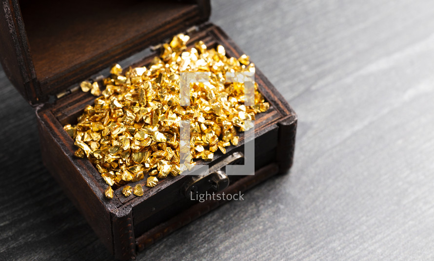 pieces of Gold in a Treasure Chest on a Wooden Table