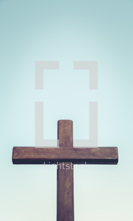 Empty wooden cross against a blue sky