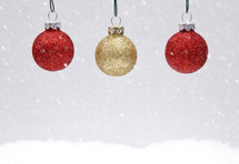 hanging red and gold ornaments in snow 