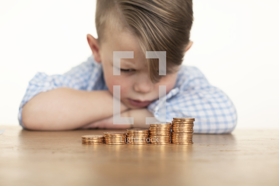 a little boy looking at his stack of coins. 