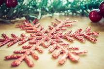 glittery red snowflake ornament and garland on a wood background 
