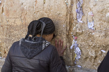 a woman praying against a wall 