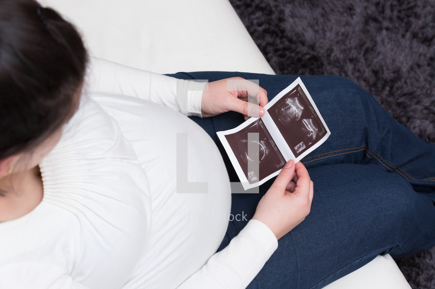 pregnant woman looking at ultrasound photos 