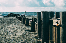 A wooden pier reaching from the beach to the sea.