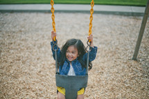 A little girl on a swing at the playground.