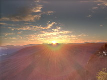 sunburst at sunset moving behind a mountain