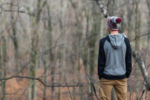 a teen boy standing in a forest in fall 