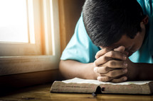 a man praying over a Bible 