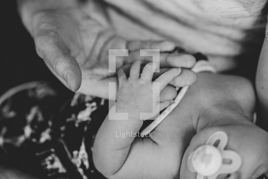 a father and newborn holding hands 