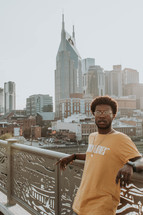 a man posing with a city view behind him 
