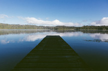 Wooden pier on a lake surrounded by trees.