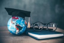 globe with graduation cap on a desk in a classroom 