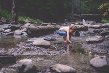 toddler boy exploring a stream 