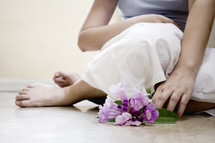 legs of a woman sitting on the floor with flowers 