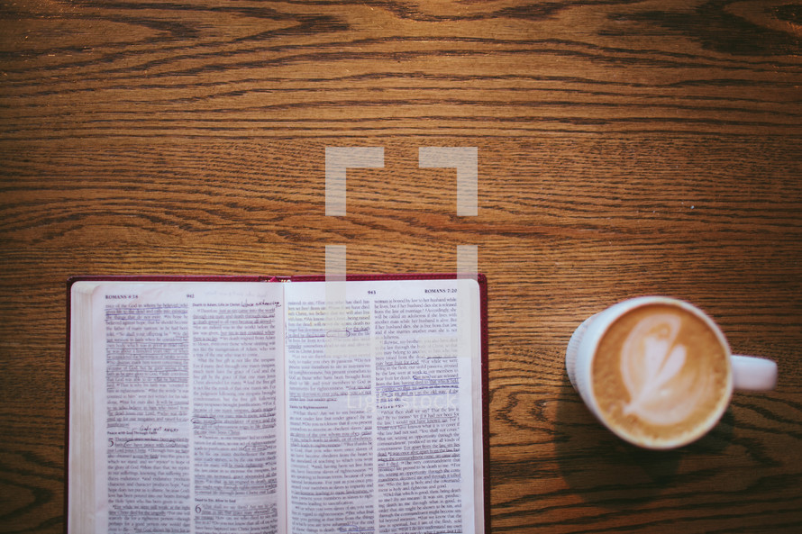 open Bible and coffee mug on a wood table 