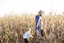 Man and daughter in field of corn stalks