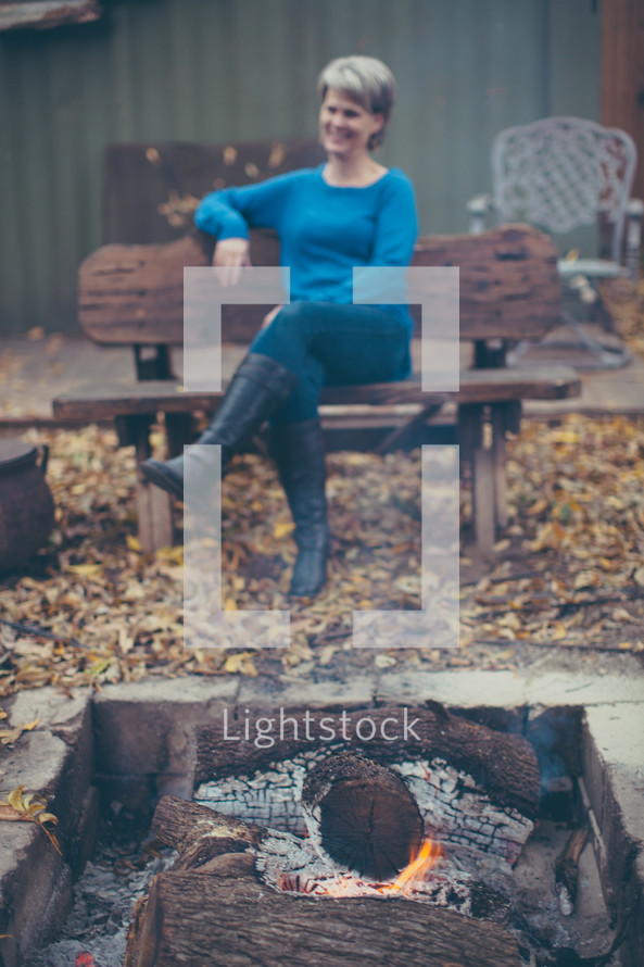 a woman sitting by a fire pit 