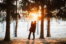 couple standing in the woods at sunset 