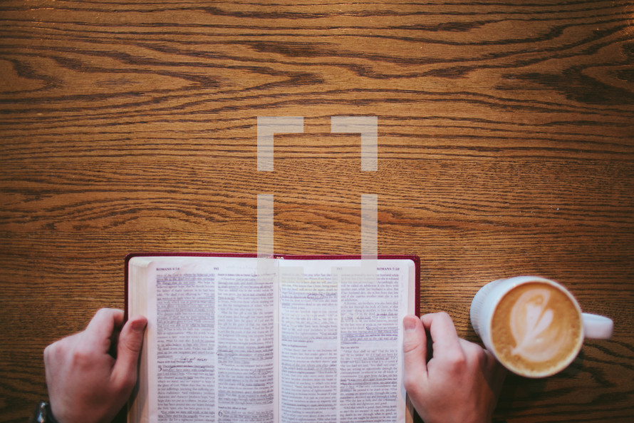 man reading a Bible and a mug of coffee 