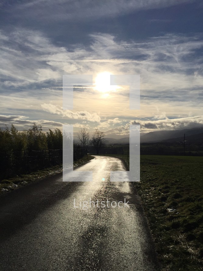 sunlight on a wet rural paved road 