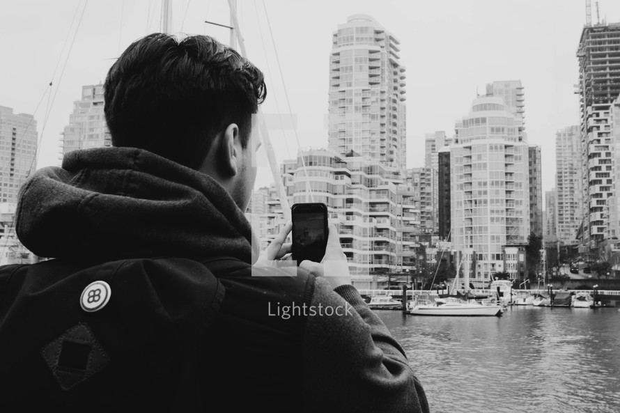 a man on a boat taking pictures of a city 
