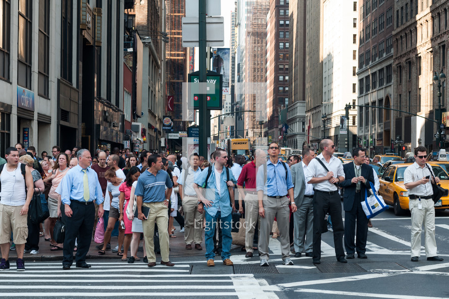 crowd of pedestrians waiting to cross a busy city street 