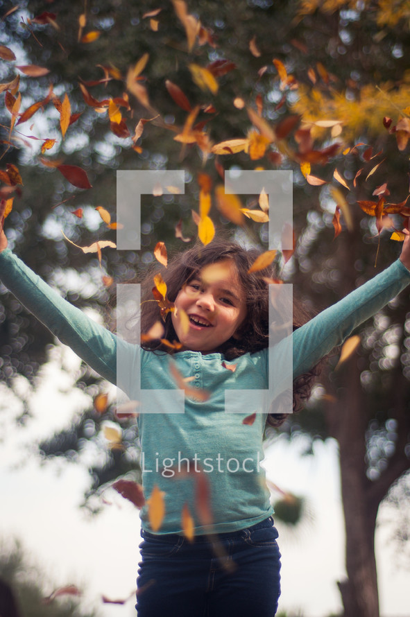  girl throwing up fall leaves 