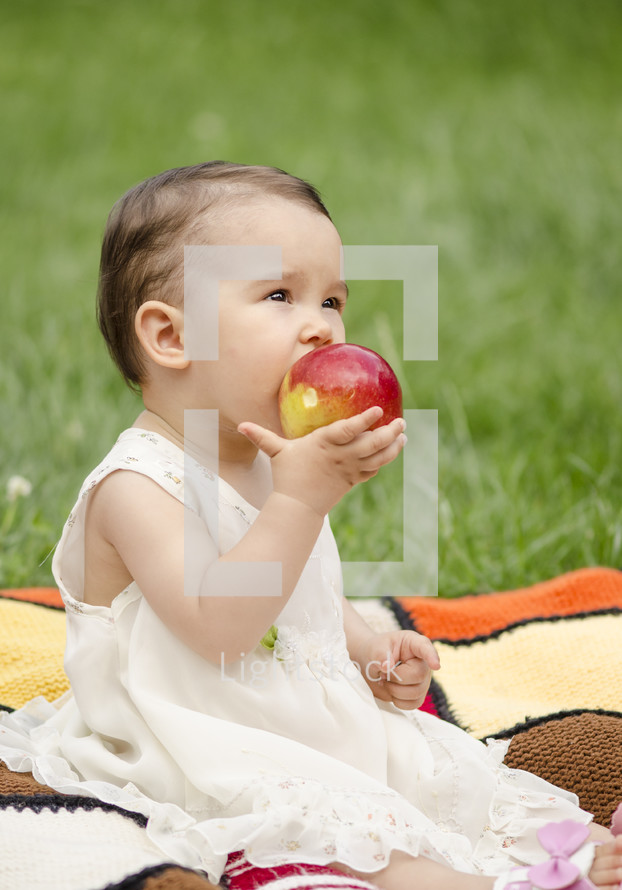toddler girl eating a red apple 