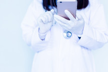 doctor with gloves looking at her cellphone 