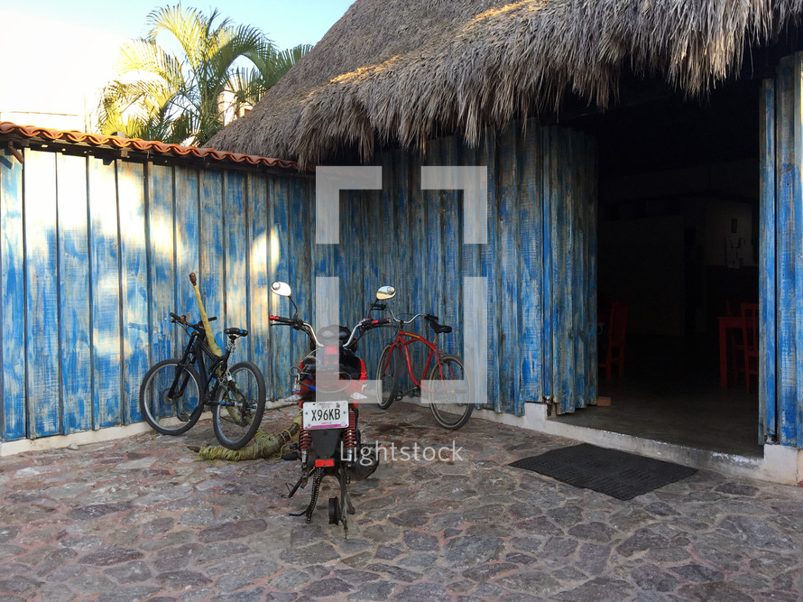 bikes parked in front of a thatched roof building 