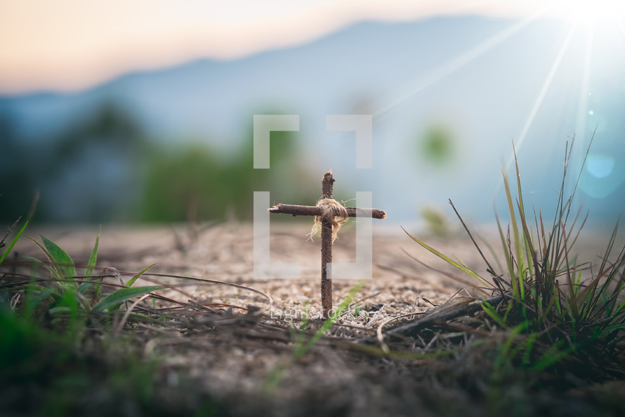 cross in the ground and mountains in the background 