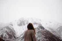 a woman looking up a snow covered mountain peak 