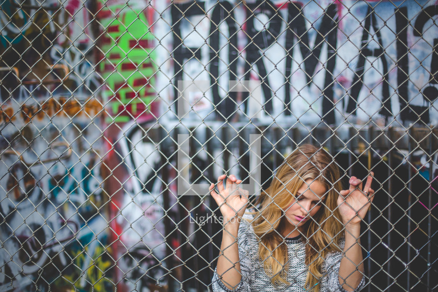 a woman clinging to a chain link fence