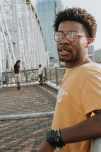 a man posing on a bridge in a city 
